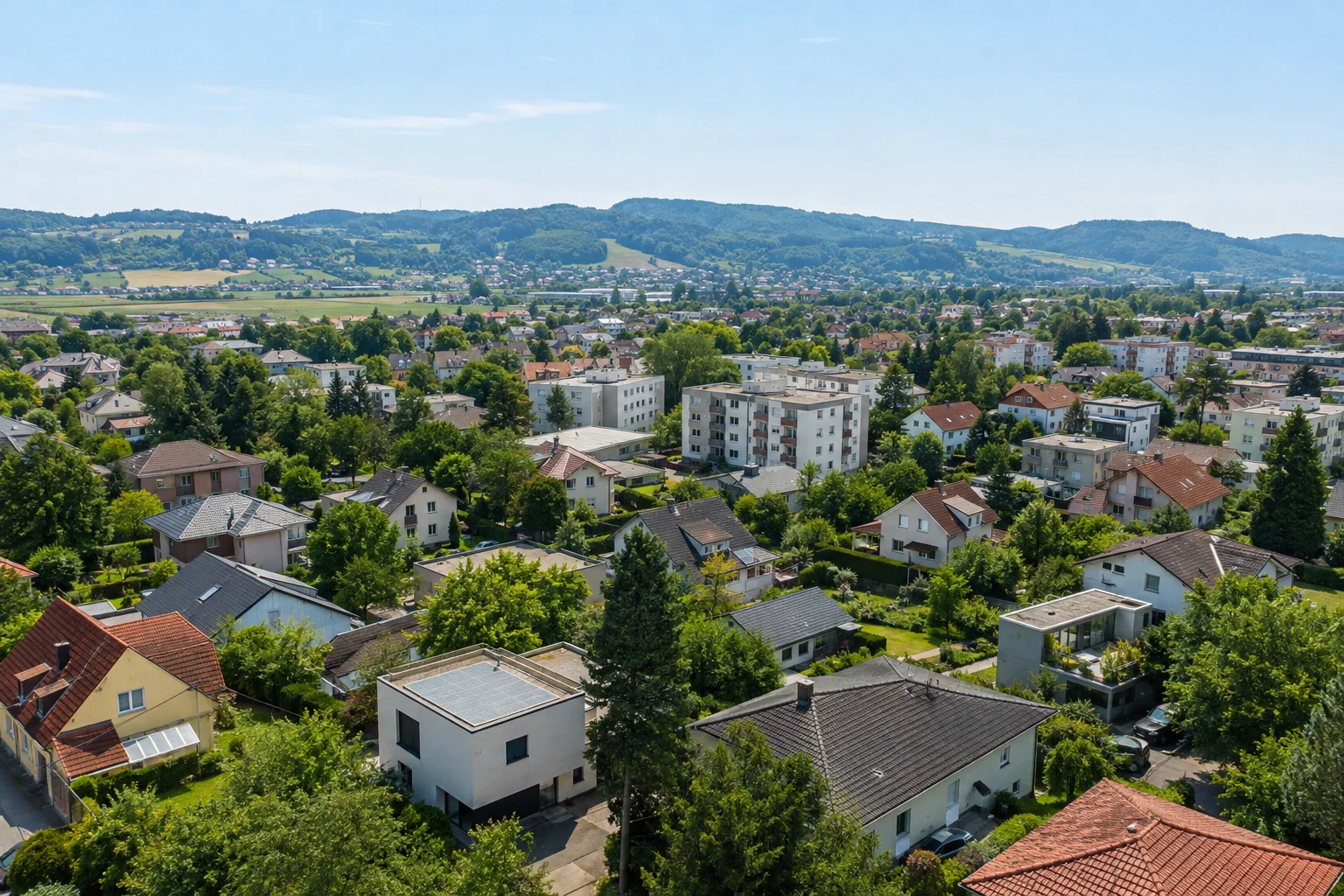 Österreichischer Stadtrand mit Häusern, Wohngebäuden, viel Grün und bewaldeten Höhen