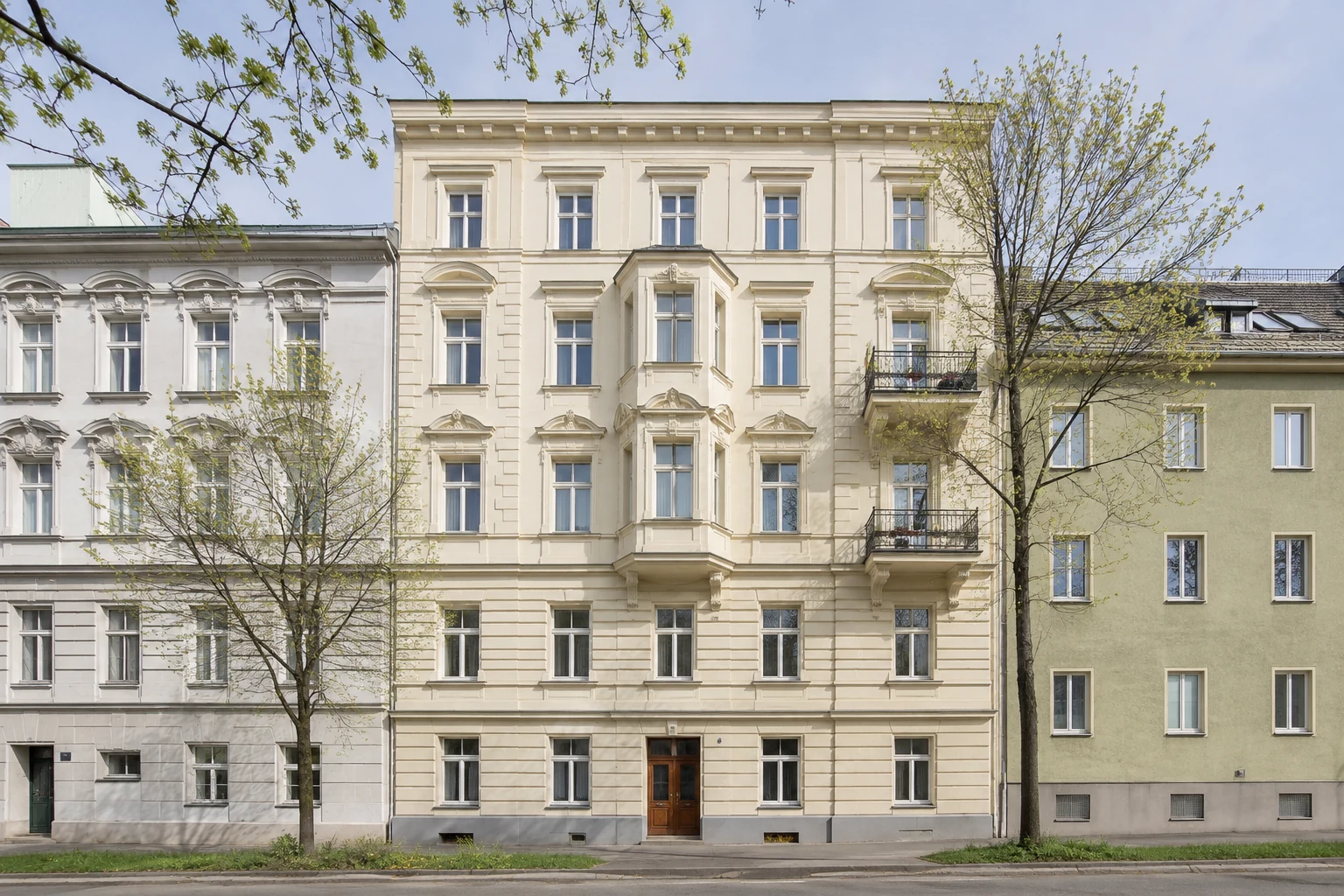 Gepflegtes österreichisches Mehrparteienhaus mit gegliederter heller Fassade und Bäumen